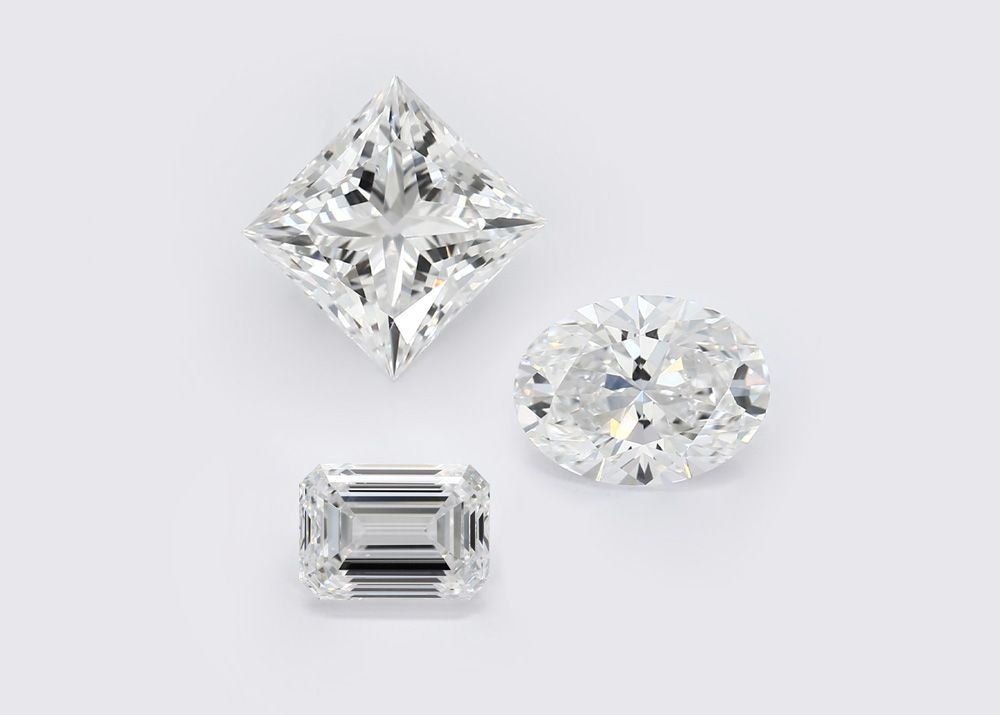 three lab-grown diamonds of various shapes and cuts on white background